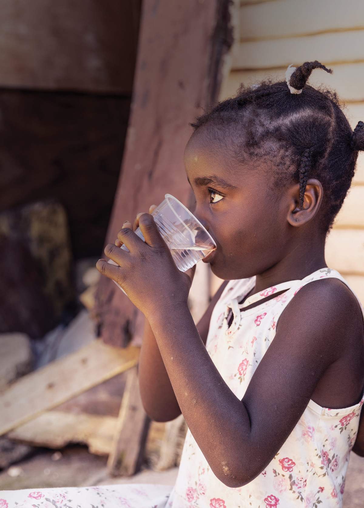 A young girl drinks a cup of clean water