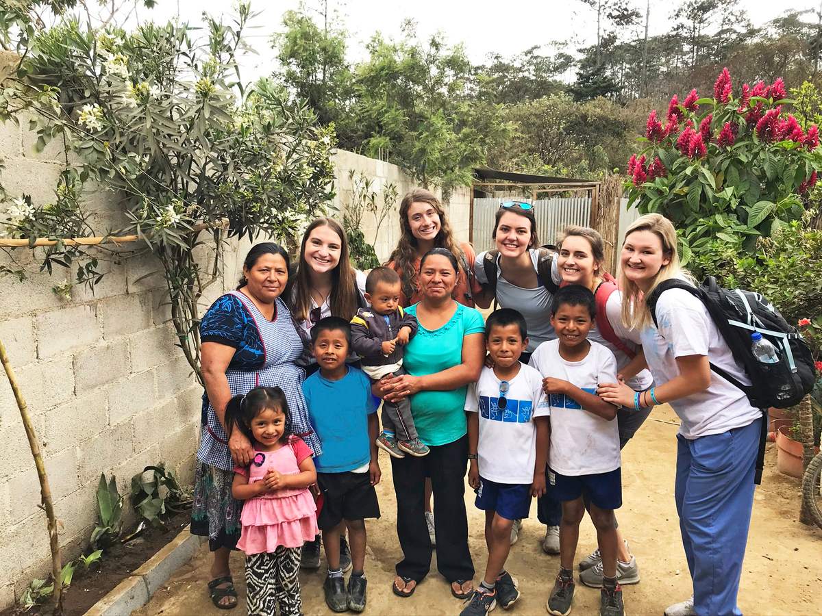 A mission team and local children gather together outside a home