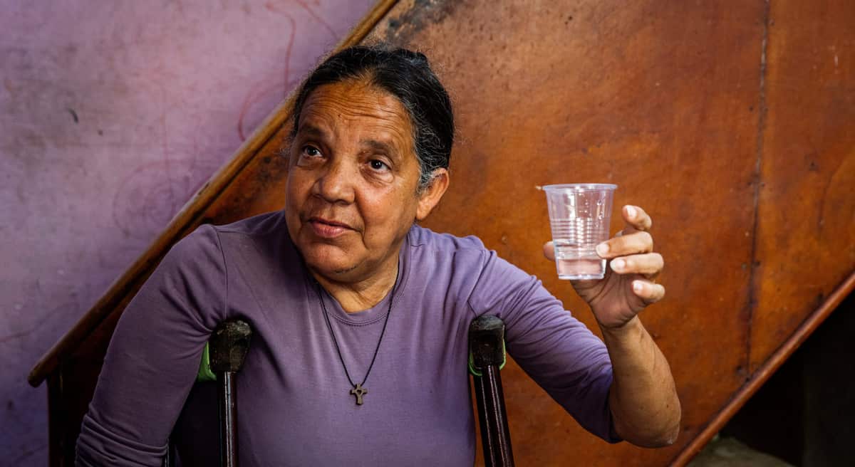 A woman in Cuba raises a cup of clean water and smiles