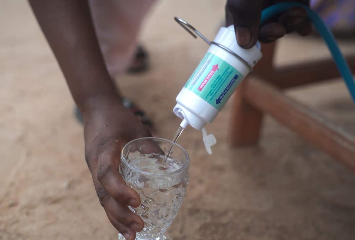 Clean water pours from a Filter of Hope filter into a cup