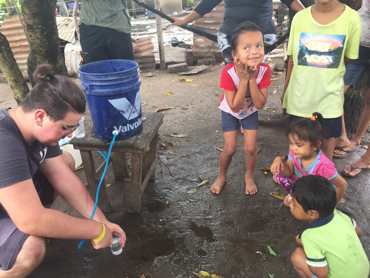 Children watch clean water pour from a filter
