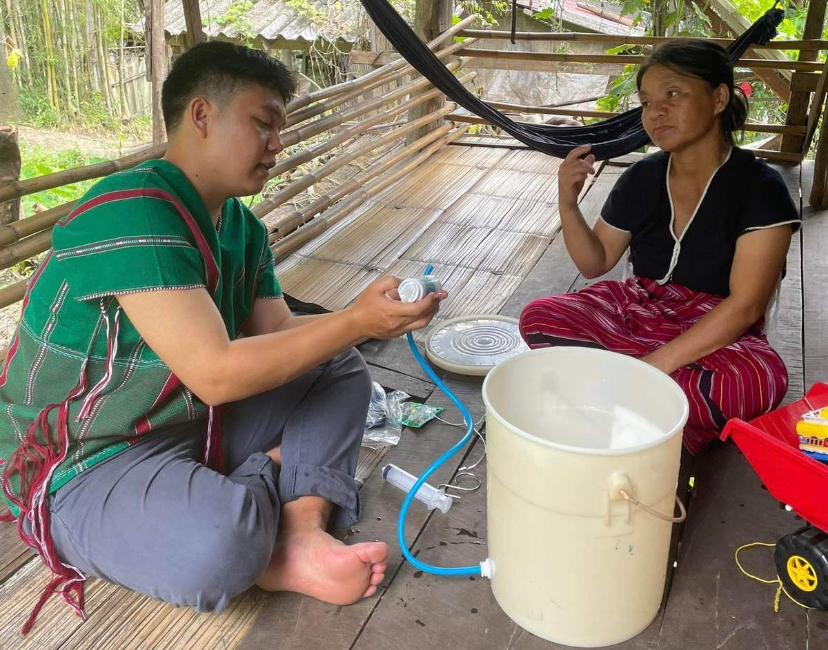 A ministry worker sets up a filter bucket with a woman in her home