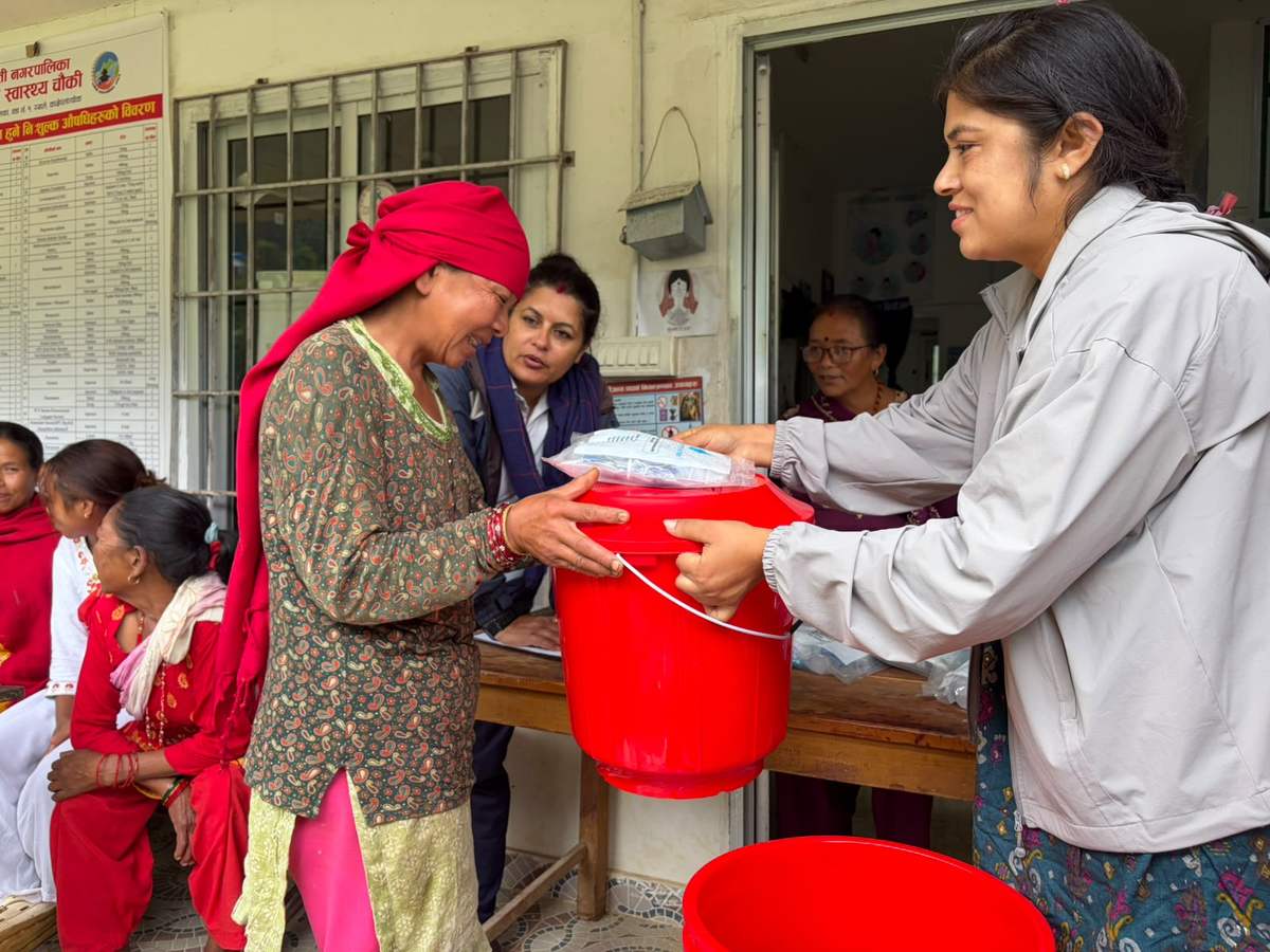 A worker hands a filter bucket to a woman in Nepal