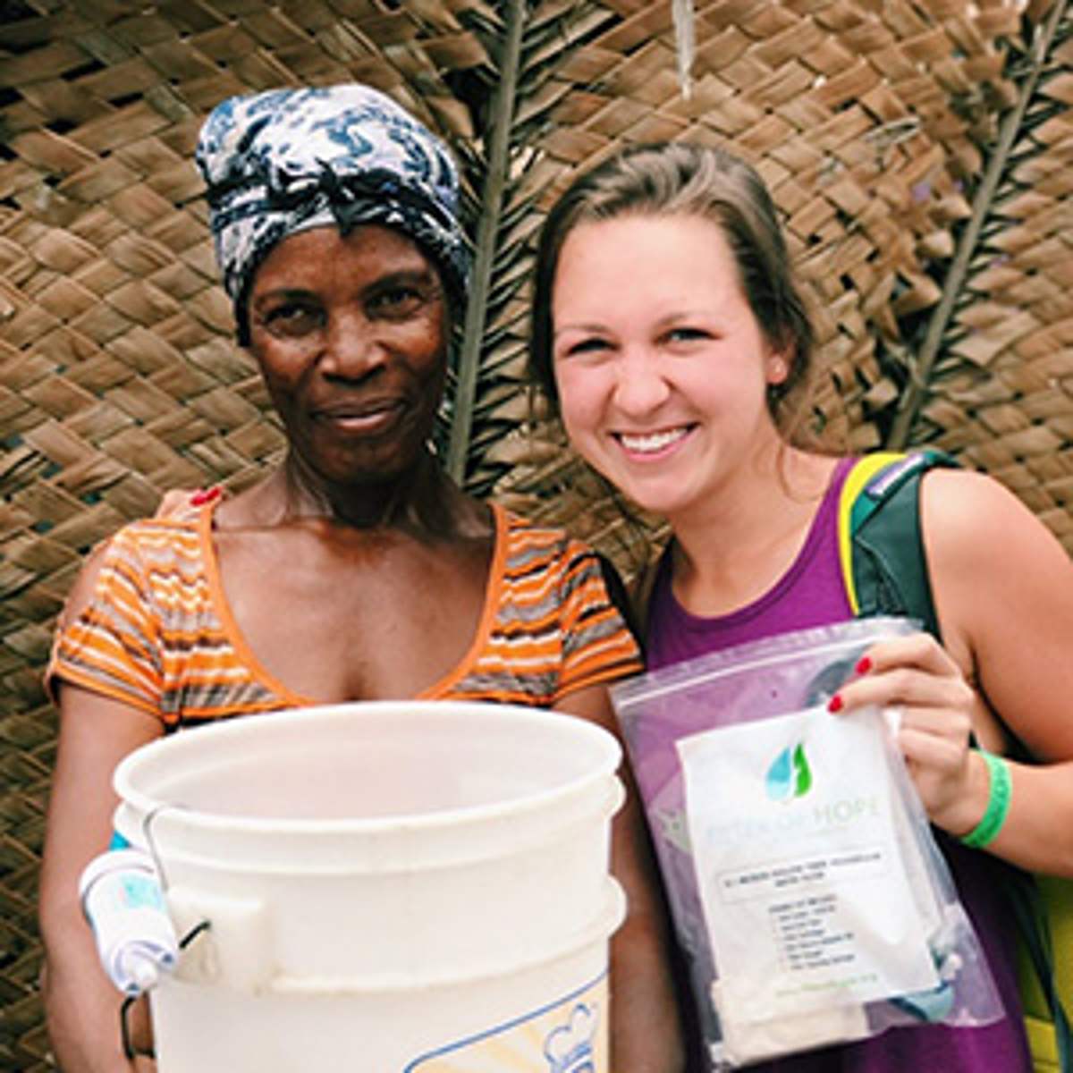 A local woman and a trip member smile with a new filter bucket