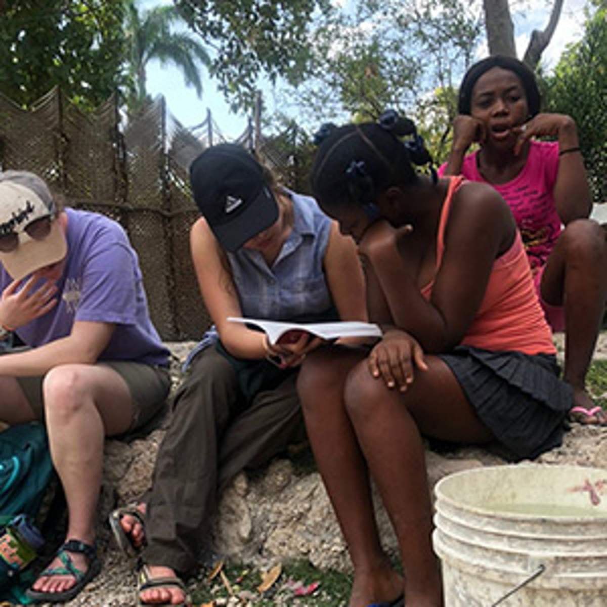 Trip members read the Bible with a woman outside her home