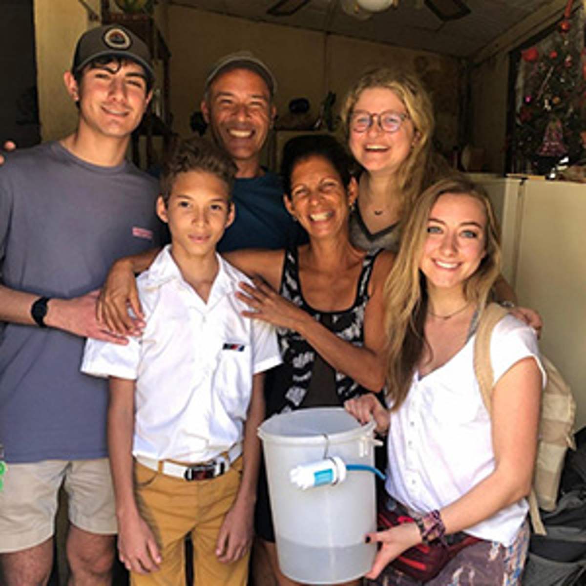 A mission team stands with a local family and their new filter bucket