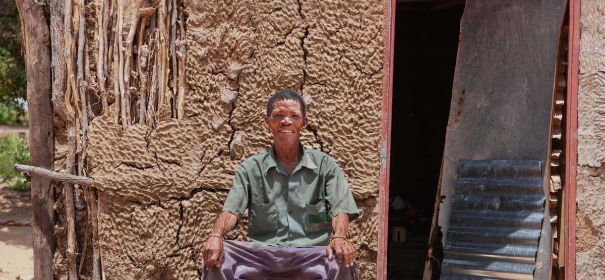 A man sits outside a mud-brick home in Nigeria
