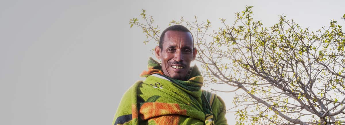 A smiling man wrapped in a green shawl in Ethiopia
