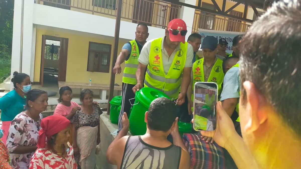 Relief workers in vests set up filters with families in Nepal