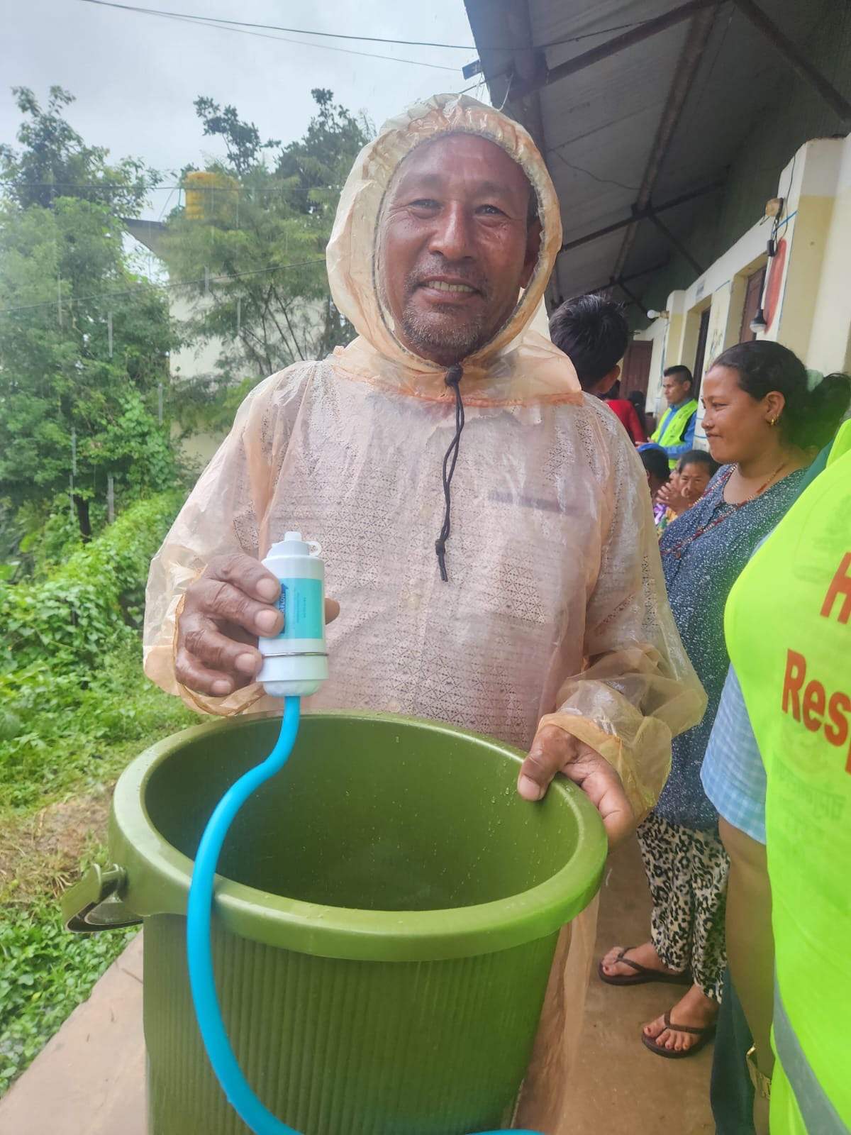 A flood survivor in Nepal fills a cup from his new filter