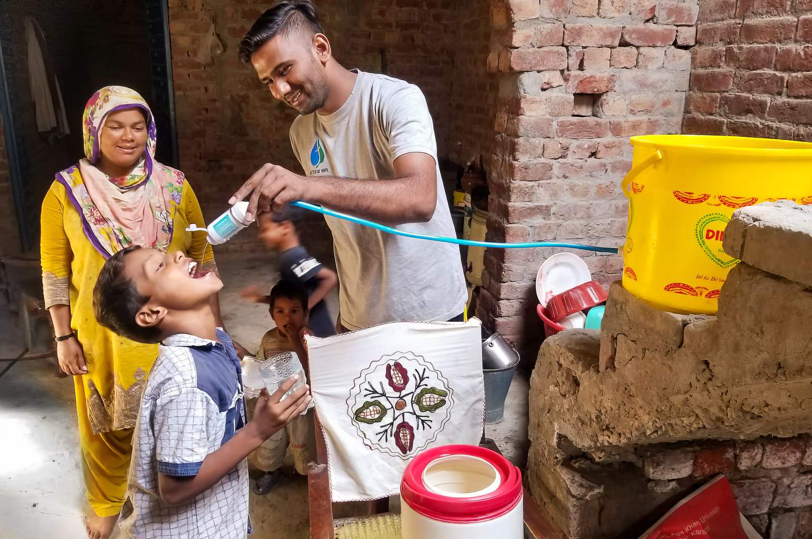 A young boy drinks clean water as a ministry worker holds the cup